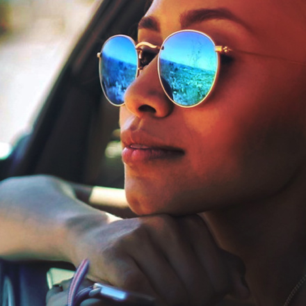 Woman with sunglasses leaning out a car window.