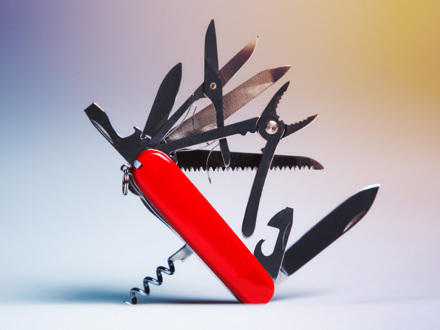 A multifunctional Swiss army knife with a red handle is opened, displaying various tools such as scissors, pliers, a knife, a corkscrew, and a file against a gradient background.