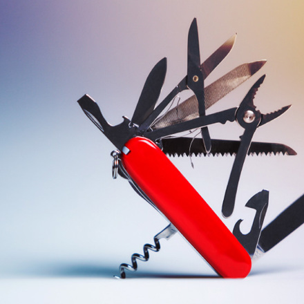 A multifunctional Swiss army knife with a red handle is opened, displaying various tools such as scissors, pliers, a knife, a corkscrew, and a file against a gradient background.