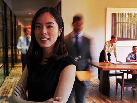 Portrait of young Asian woman in a busy modern workplace