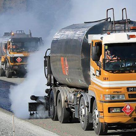 Isaac Construction trucks sealing a road