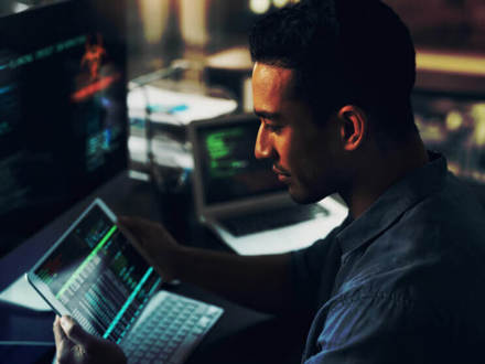 A young man using his digital tablet and computer in a modern office