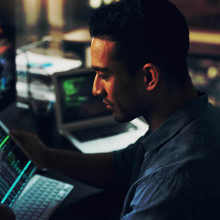 A young man using his digital tablet and computer in a modern office