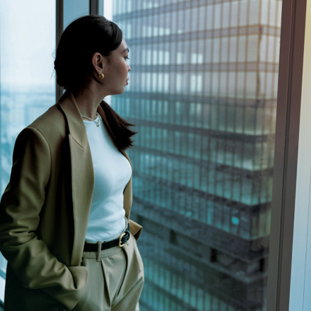 Woman standing at window of skyscraper