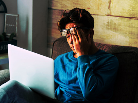 Stressed student at home studying with personal laptop computer