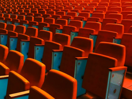 Rows and rows of empty orange auditorium chairs.