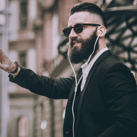 Man hailing a taxi while wearing earphones.