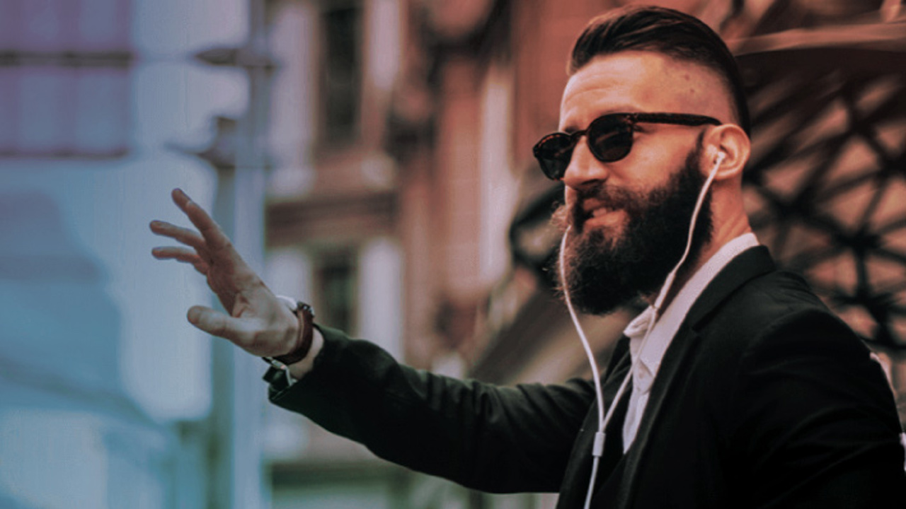 Bearded guy with headphones on, signalling to someone to talk about their ERP system.   