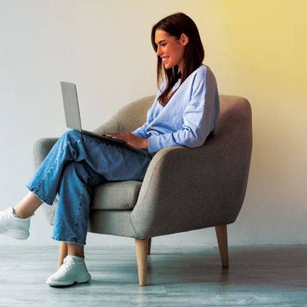 Content woman sitting in grey chair working on laptop