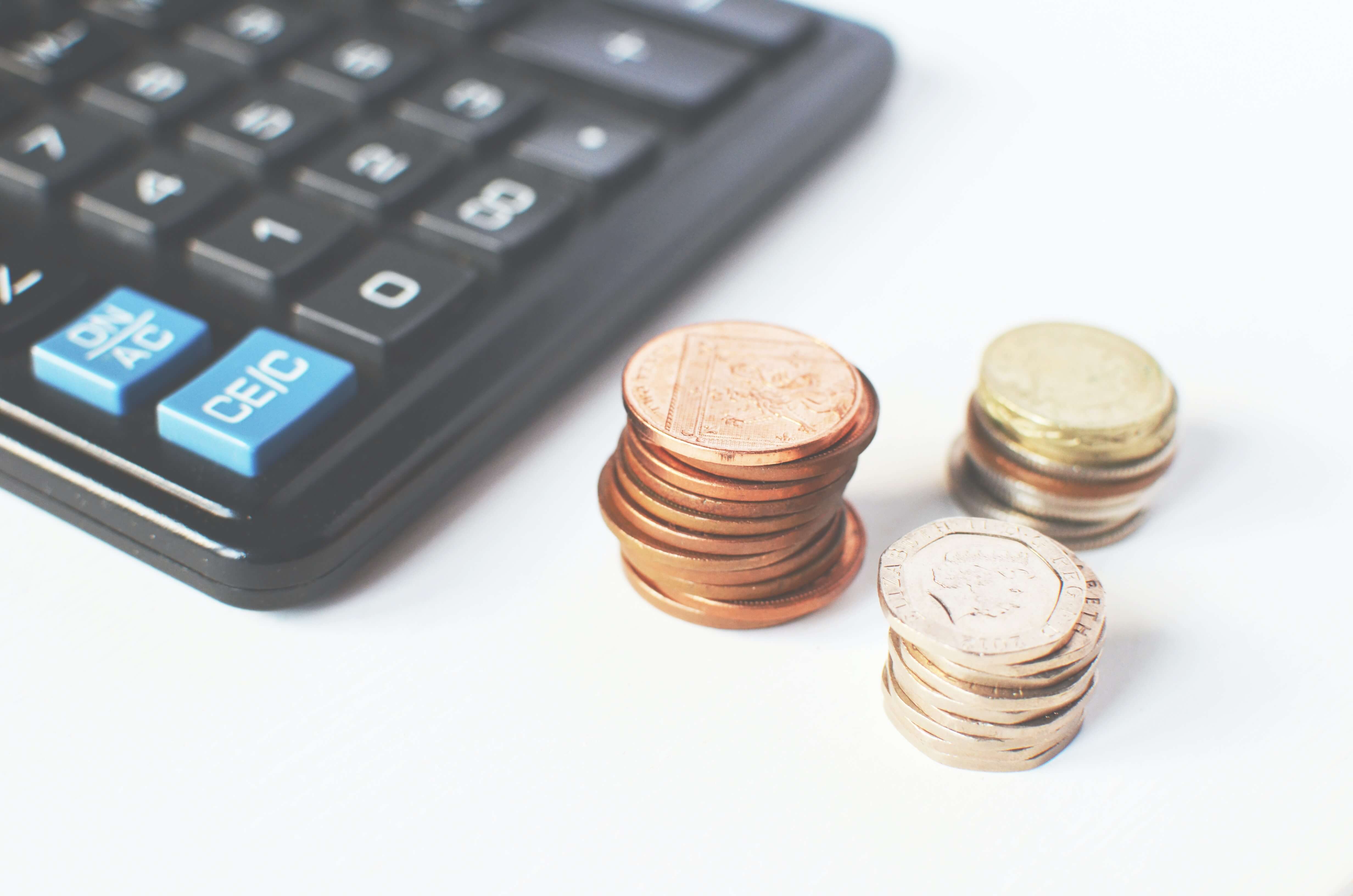 Calculator and three stacks of coins. 